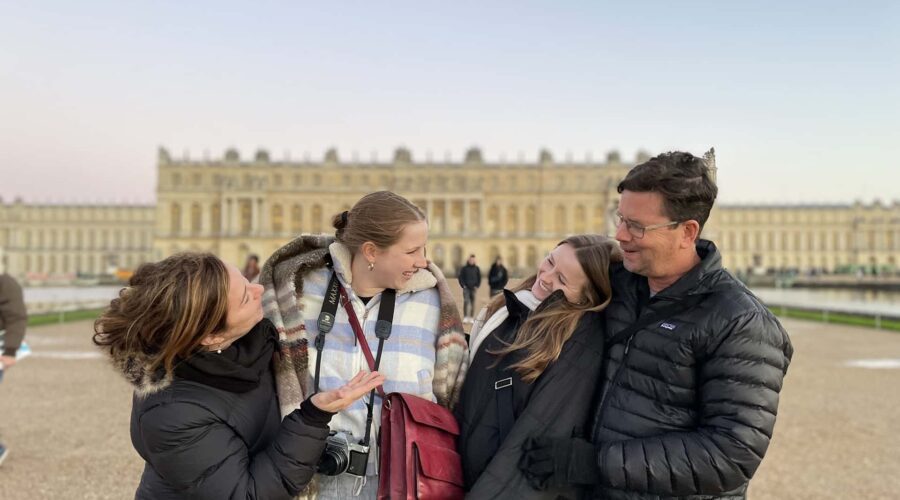 Family enjoying guided Versailles Palace tour with transfers from Paris in royal gardens