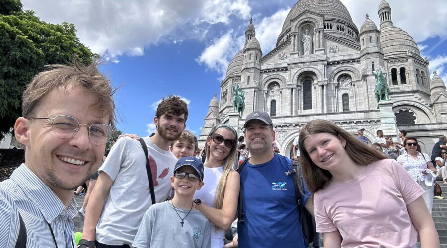 Guide and family smiling on the steps of Sacré-Cœur, enjoying views from a private Montmartre tour.