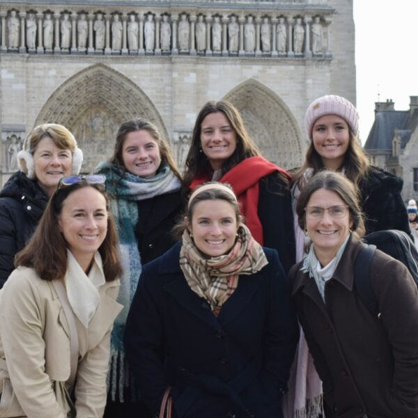 Three generations of women smile together in front of the sculpted façade of Notre-Dame Cathedral during a private family tour in Paris