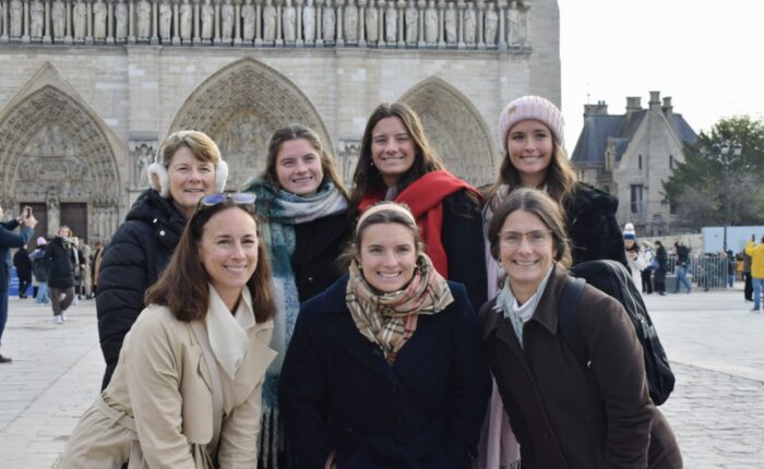 Three generations of women smile together in front of the sculpted façade of Notre-Dame Cathedral during a private family tour in Paris
