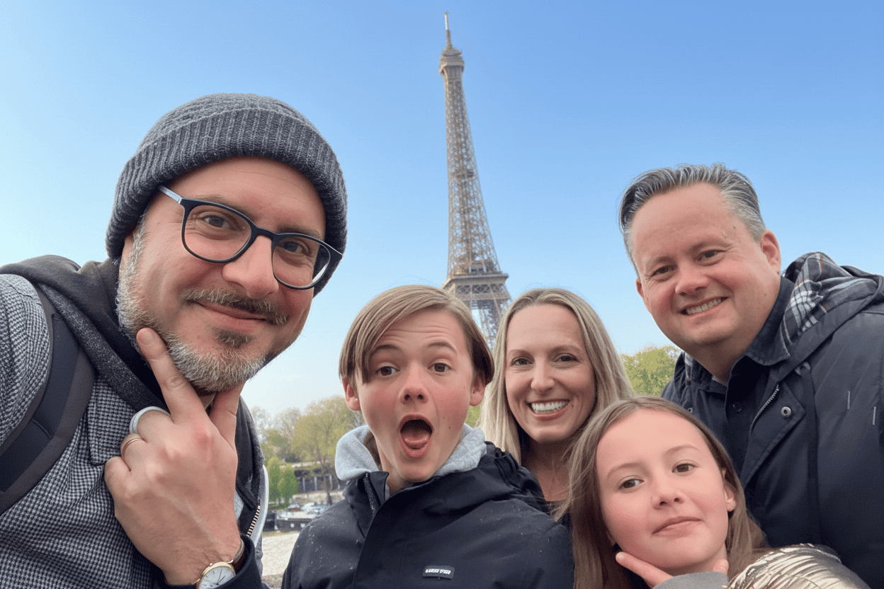 Smiling family and their guide taking a selfie in front of the Eiffel Tower during a private Paris city tour.