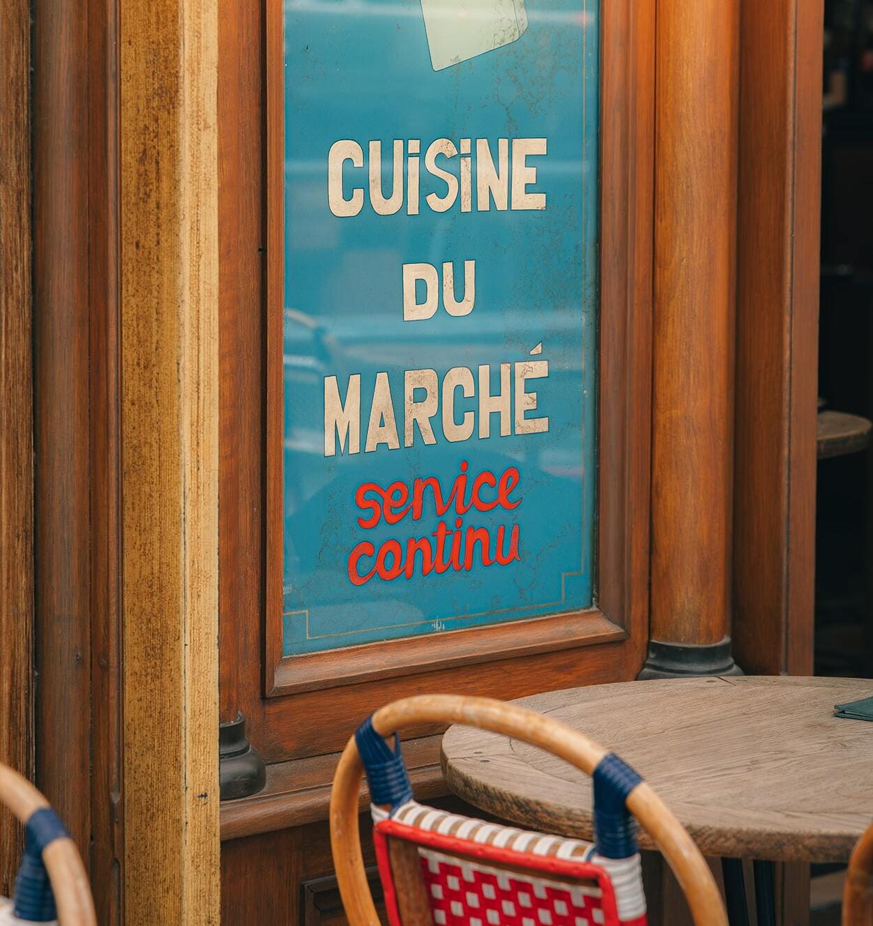 Traditional Paris bistro terrace with Cuisine du Marché sign, authentic French dining experience