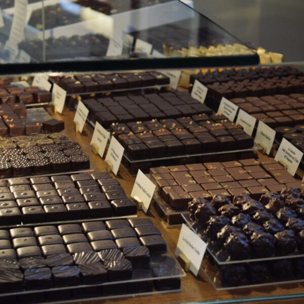 Neatly arranged rows of artisan chocolates behind glass in a Paris boutique, featured on a private Marais food tour