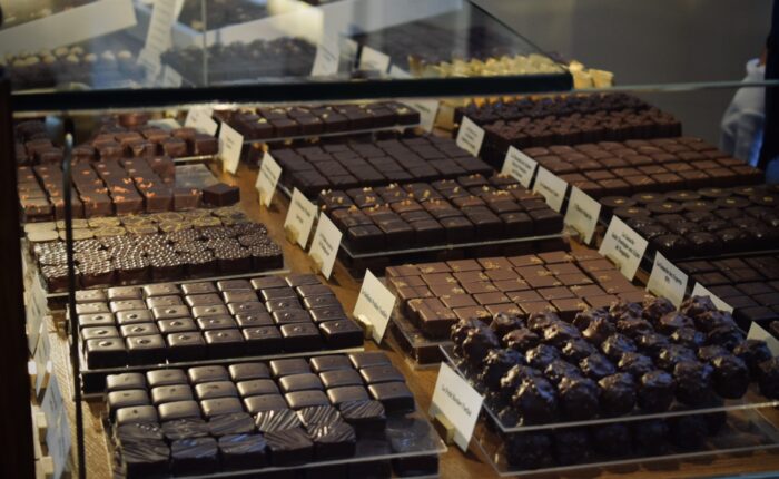 Neatly arranged rows of artisan chocolates behind glass in a Paris boutique, featured on a private Marais food tour
