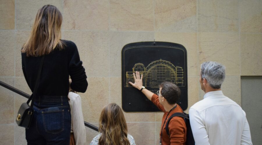 Guide showing a family the architectural plan of Orsay Museum on a wall plaque during a private tour