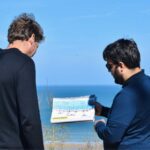 Paris and Beyond Tours guide explaining Omaha Beach D-Day tactical map to guest overlooking landing sectors - private WWII history tour from Bayeux Caen