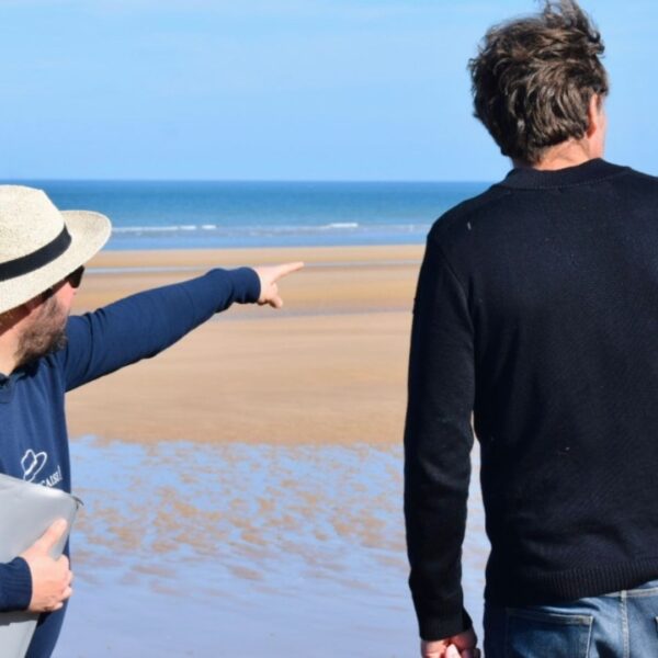 Paris and Beyond Tours expert guide explaining D-Day landing sectors at low tide Normandy beach - private World War II history tour from Bayeux Caen